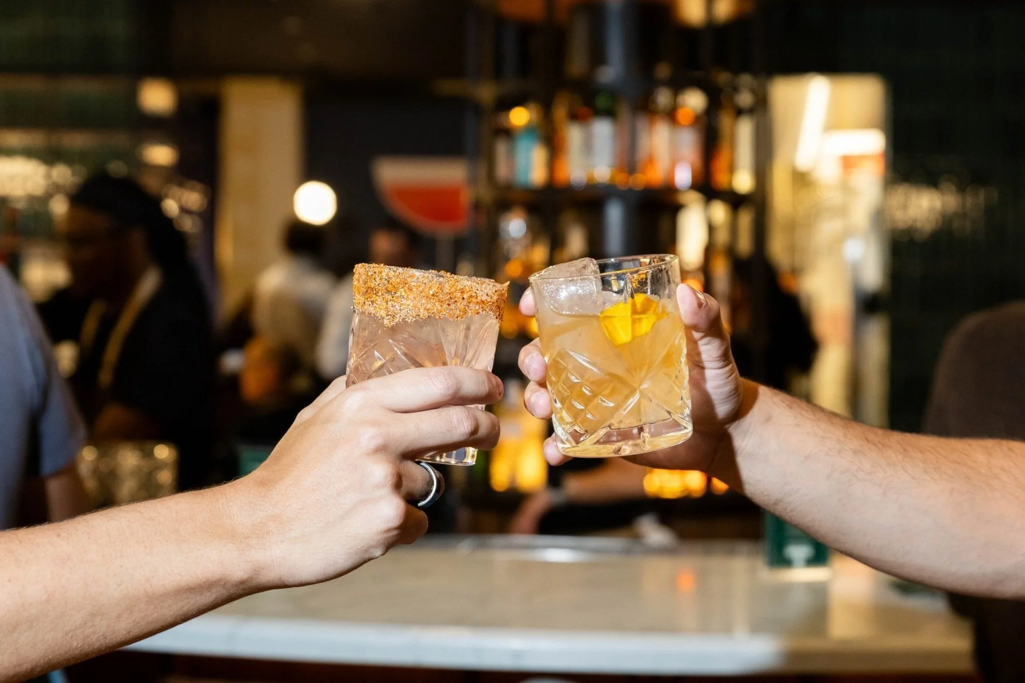 Two guests toasting cocktails at the bar